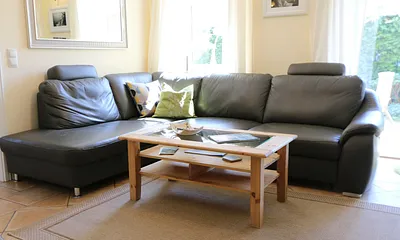 gemütlicher Wohnbereich mit einer großen Couchecke, Couchtisch, Leselampe, Sideboard, Flachbild-TV und Mini-Stereo-Anlage