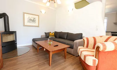 Wohnbereich mit großer Couchecke, Couchtisch, Leselampe, Sideboard, Smart-TV und Mini-Stereo-Anlage