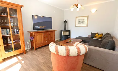 Wohnbereich mit großer Couchecke, Couchtisch, Leselampe, Sideboard, Smart-TV und Mini-Stereo-Anlage