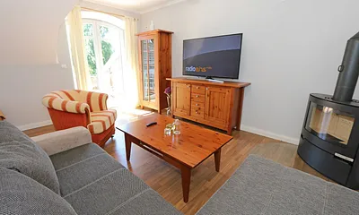 Wohnbereich mit großer Couchecke, Couchtisch, Leselampe, Sideboard, Smart-TV und Mini-Stereo-Anlage