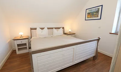Schlafzimmer mit Doppelbett (1,80 m x 2,00 m), verstellbaren Lattenrosten, Nachttischablagen, Kleiderschrank, Verdunklungsmöglichkeit und Smart-TV