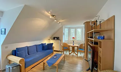 Wohnbereich mit Couch, Couchtisch sowie TV-Board, Leselampe, LCD-Flachbildschirm, Blu-Ray-Player und Mini-Stereo-Anlage sowie Insektenschutzgitter