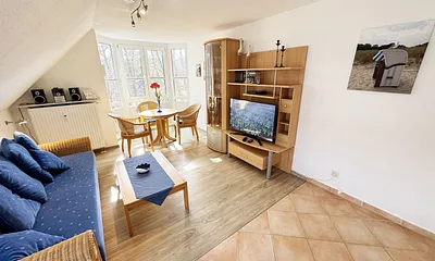 Wohnbereich mit Couch, Couchtisch sowie TV-Board, Leselampe, LCD-Flachbildschirm, Blu-Ray-Player und Mini-Stereo-Anlage sowie Insektenschutzgitter