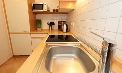 Küche mit Geschirrspüler, Cerankochfeld, Backofen, Kühlschrank mit Gefrierfächer, Mikrowelle, Kaffeemaschine, Senseopad-Maschine, Wasserkocher, Toaster sowie diverse Küchenutensilien