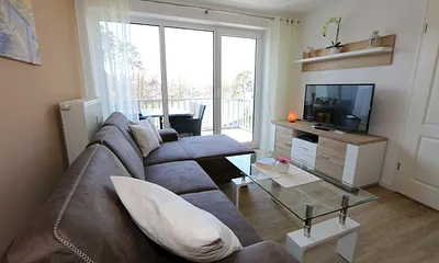 Wohnbereich mit gemütlicher Couch (Aufbettung für 3. Person 1,20 m x 2,00 m), Leselampe, Couchtisch, TV-Board mit Smart-TV, Blu-Ray-Player und Mini-Stereo-Anlage