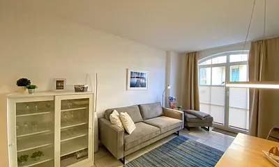 Wohnbereich mit bodentiefen Fenstern, 3-Sitzer-Couch, Couchtisch, Smart-TV, DVD-Player, Radio mit CD-Player und USB-Anschluss sowie eine Alexa-Box