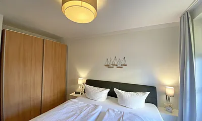 Schlafzimmer mit Echtleder-Doppelbett in Komforthöhe (2 x 0,90 m x 2,00 m), mit Nachttischablagen, Insektenschutzgittern, Verdunklungsmöglichkeit und einen großem Kleiderschrank