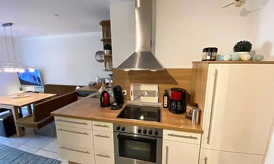 angrenzende Pantry-Küche mit Edelstahlspüle, 4-Zonen-Cerankochfeld, Kühlschrank mit Gefrierfach, Geschirrspüler, Mikrowelle, Dunstabzugs-Kombination, Kaffeemaschine, Wasserkocher und Toaster