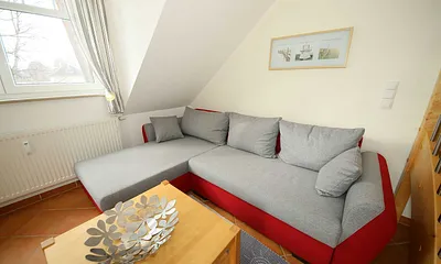 Wohnzimmer mit gemütlicher Couchecke, Couchtisch und Leselampe sowie ein Smart-TV und ein DAB-Radio mit CD-Player