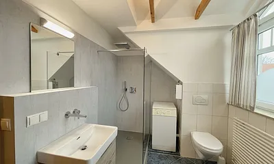 Badezimmer mit Dusche, WC, Fön, Waschmaschine (Münzgerät) sowie Fußbodenheizung und Handtuchtrockner