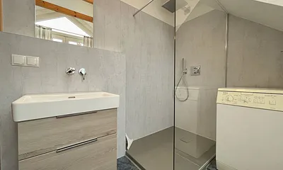 Badezimmer mit Dusche, WC, Fön, Waschmaschine (Münzgerät) sowie Fußbodenheizung und Handtuchtrockner