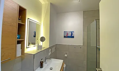 innenliegendes Badezimmer mit Waschtisch, Wandspiegel, ebenerdiger Regendusche, WC, Fön und Handtuchtrockner