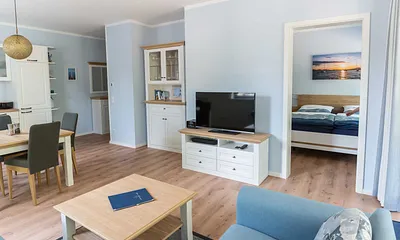 offener Wohnbereich mit bequemer Couch (Aufbettung 3. Person 1,60 m x 2,00 m), Sessel, Couchtisch, Stehlampe, Sideboard, Vitrine, Smart-TV sowie ein DAB Radio mit Bluetooth