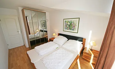 Schlafzimmer mit Doppelbett, Nachttischkonsolen und einen großen Kleiderschrank