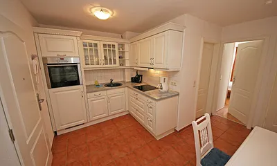 offene Küchenzeile mit Ceranfeld, Backofen, Geschirrspüler, Kühlschrank, Kaffeemaschine, Wasserkocher, Toaster sowie diverse Küchenutensilien