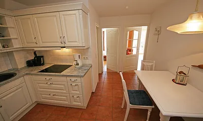 offene Küchenzeile mit Ceranfeld, Backofen, Geschirrspüler, Kühlschrank, Kaffeemaschine, Wasserkocher, Toaster sowie diverse Küchenutensilien