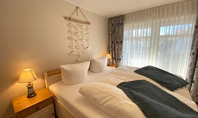 Schlafzimmer mit Doppelbett (1,80 m x 2,00 m), Nachttischablagen mit Lampen und einen Kleiderschrank