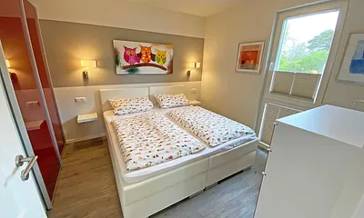 Schlafzimmer mit Boxspringbett (1,80 m x 2,00 m, durchgehender Topper in Komforthöhe), Nachttischablagen mit Wandleuchten,großzügiger Kleiderschrank, Kommode sowie ein Herrendiener