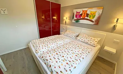 Schlafzimmer mit Boxspringbett (1,80 m x 2,00 m, durchgehender Topper in Komforthöhe), Nachttischablagen mit Wandleuchten,großzügiger Kleiderschrank, Kommode sowie ein Herrendiener