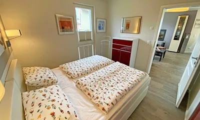 Schlafzimmer mit Boxspringbett (1,80 m x 2,00 m, durchgehender Topper in Komforthöhe), Nachttischablagen mit Wandleuchten,großzügiger Kleiderschrank, Kommode sowie ein Herrendiener