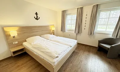 Schlafzimmer hell und modern eingerichtet mit Doppelbett, Komfortmatratzen (2x 0,90 m x 2,00 m), Nachttischkonsolen, Kleiderschrank und Verdunklungsgardinen