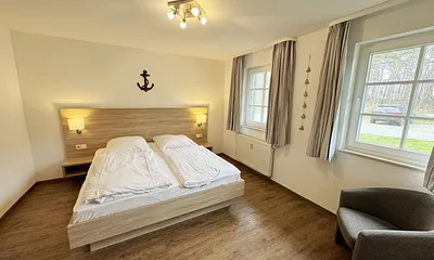 Schlafzimmer hell und modern eingerichtet mit Doppelbett, Komfortmatratzen (2x 0,90 m x 2,00 m), Nachttischkonsolen, Kleiderschrank und Verdunklungsgardinen
