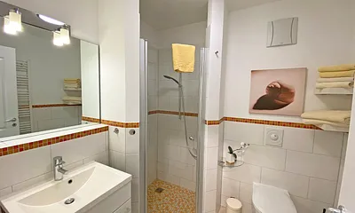 innenliegendes Badezimmer mit ebenerdiger Dusche, Waschbecken mit Unterschrank, Handtuchheizkörper, Fön, Kosmetikspiegel und WC