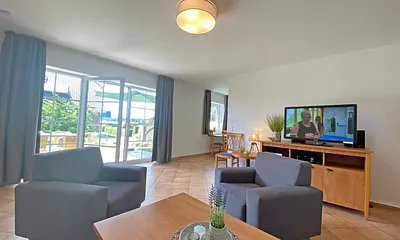 Wohnbereich mit Massivmöbeln, Stehlampe, zwei Sessel und zwei Schlafcouchen (Aufbettung für 5./6. Person - 1,90 m x 2,00 m), 42 Zoll LCD-TV, CD und DVD-Player sowie Gesellschaftsspiele