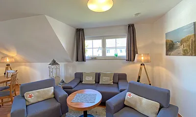 Wohnbereich mit Massivmöbeln, Stehlampe, zwei Sessel, Couch, LCD-TV und ein CD/ DVD-Player