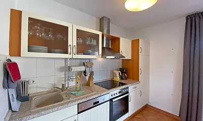 Küchenzeile mit Geschirrspüler, Mikrowelle, Ceranfeld, Backofen, Kühlschrank, Wasserkocher, Toaster, Kaffeemaschine und diversen Küchenutensilien 