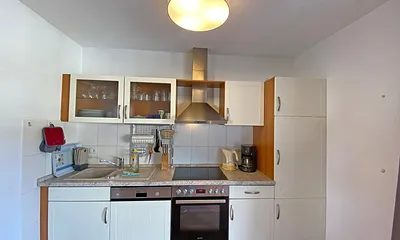 Küchenzeile mit Geschirrspüler, Mikrowelle, Ceranfeld, Backofen, Kühlschrank, Wasserkocher, Toaster, Kaffeemaschine und diversen Küchenutensilien 