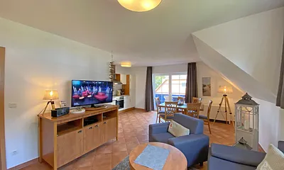 Wohnbereich mit Massivmöbeln, Stehlampe, zwei Sessel, Couch, LCD-TV und ein CD/ DVD-Player