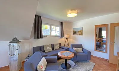 Wohnbereich mit Massivmöbeln, Stehlampe, zwei Sessel, Couch, LCD-TV und ein CD/ DVD-Player