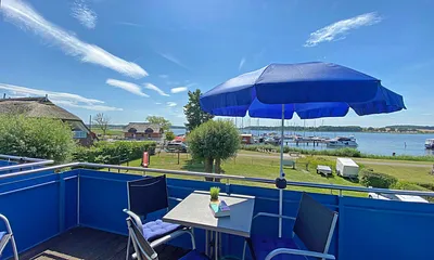 großer bestuhlter Balkon (West) mit Sonnenschirm und Panoramablick auf den Selliner See 