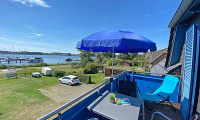 großer bestuhlter Balkon (West) mit Sonnenschirm und Panoramablick auf den Selliner See 