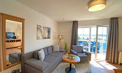 Wohnbereich mit Massivmöbeln, Stehlampe, zwei Sessel und einer Schlafcouch (Aufbettung für 3./4. Person, 1,90 m x 2,00 m), 42 Zoll LCD-TV, CD/ DVD-Player und Gesellschaftsspiele 