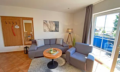 Wohnbereich mit Massivmöbeln, Stehlampe, zwei Sessel und einer Schlafcouch (Aufbettung für 3./4. Person, 1,90 m x 2,00 m), 42 Zoll LCD-TV, CD/ DVD-Player und Gesellschaftsspiele 