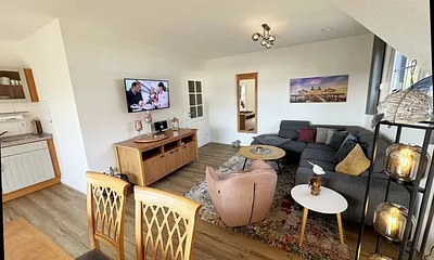 Wohnbereich mit Couch, Sessel, Couchtisch, Sideboard, Smart-TV, CD-Player und ein Radio 