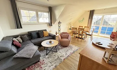 Wohnbereich mit Couch, Sessel, Couchtisch, Sideboard, Smart-TV, CD-Player und ein Radio 