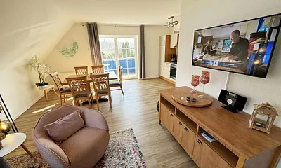 Wohnbereich mit Couch, Sessel, Couchtisch, Sideboard, Smart-TV, CD-Player und ein Radio