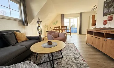 Wohnbereich mit Couch, Sessel, Couchtisch, Sideboard, Smart-TV, CD-Player und ein Radio