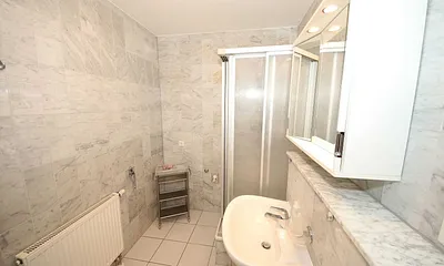 Badezimmer mit Marmorfliesen, Dusche, Kosmetikspiegel, Waschtisch, Fön und WC