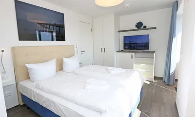 Schlafzimmer mit Boxspringbetten ( Doppelbett 1,60 m x 2,00 m ), Smart-TV, Nachttischablagen mit Beleuchtung und USB-Anschlüssen sowie Kleiderschränken