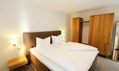 Schlafzimmer ist mit einem Boxspringbett (1,80 m x 2,00 m), durchgehenden Topper, Nachttischablagen, Kosmetiktisch, Kleiderablage sowie einen Kleiderschrank