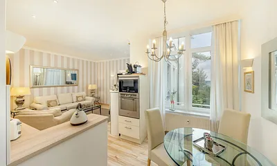 Blick über die Küchenzeile mit Backofen und Mikrowelle in den Wohnraum.