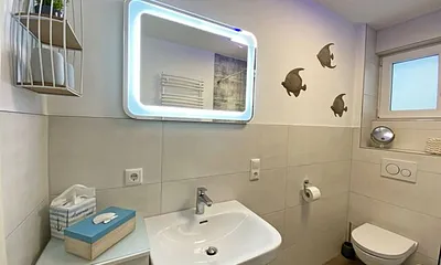 Tageslicht-Bad mit offener Glasdusche mit niedrigem Einstieg, Waschplatz, WC, Kosmetikspiegel, Fön, Handtuchtrockner sowie eine Fußbodenheizung