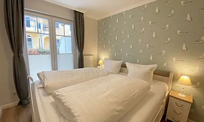 Schlafzimmer mit Doppelbett in Komforthöhe (1,80 m x 2,00 m), verstellbare Lattenroste, Nachtischablagen mit Lampen sowie ein zweitüriger Kleiderschrank