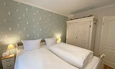 Schlafzimmer mit Doppelbett in Komforthöhe (1,80 m x 2,00 m), verstellbare Lattenroste, Nachtischablagen mit Lampen sowie ein zweitüriger Kleiderschrank