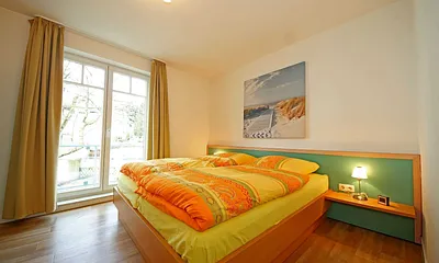 Schlafzimmer mit Doppelbett (1,80 m x 2,00 m), Schrank, Ablageflächen und bodentiefe Fenster mit Verdunklungsvorhängen