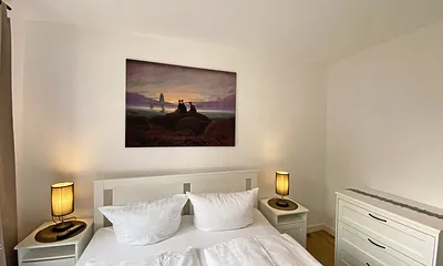 Schlafzimmer mit Doppelbett (1,60 m x 2,00 m, H3), Nachttischablagen, Kleiderschrank, Kommode, Smart-TV sowie Verdunklungsvorhang